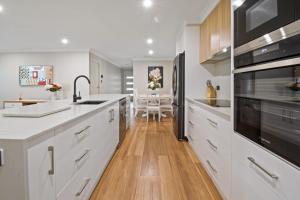 Una cocina con gabinetes blancos y un fregadero. en Thane Retreat - Cosy Ambience, Modern Entertaining, en Wagga Wagga