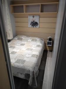 ein kleines Schlafzimmer mit einem Bett und einem Bild an der Wand in der Unterkunft Camping La Marine in Le Grau-du-Roi