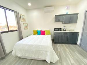 a bedroom with a white bed with colorful pillows at Apartamentos Residencias in Mexicali