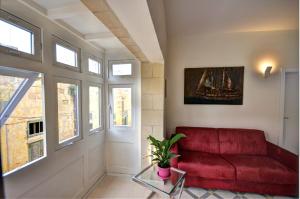 a living room with a red couch and windows at Valletta Central Apartment in Valletta