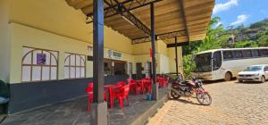 a building with red tables and chairs and a bus at Pousada Plantar e Cuidar in Santa Cruz do Escalvado