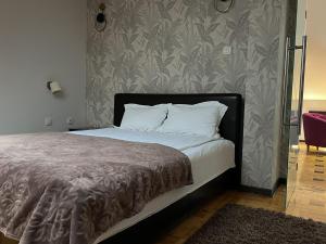a bed with white pillows and a gray wall at Pleasure Čair apartments in Niš
