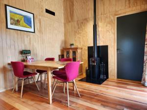 a dining room with a wooden table and pink chairs at Nevis Landing Off Grid B&B in Garston