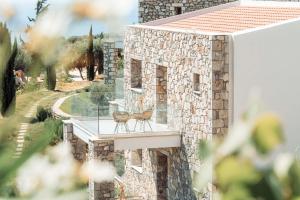 a balcony of a stone house with a table and chairs at WHITE DONKEY BOUTIQUE Hotel in Chrani