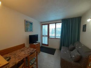 a living room with a table and a couch and a television at Studio cosy 2/3 pers, proche remontées & commerces à Valfréjus - FR-1-561-88 in Valfréjus