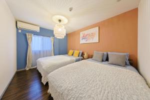 大阪市にあるRyugu -竜宮-の青とオレンジの壁の客室で、ベッド2台が備わります。