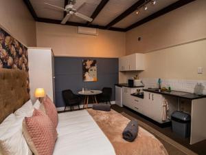a bedroom with a bed and a kitchen with a table at The Cock House in Grahamstown