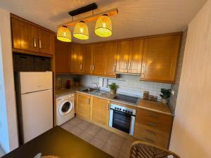a kitchen with wooden cabinets and a white refrigerator at El Olivo in Benimantell +2 photos