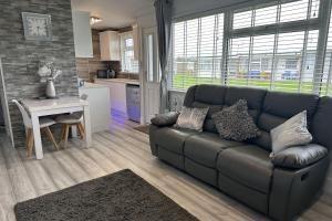 ein Wohnzimmer mit Sofa und Tisch in der Unterkunft Dog friendly chalet in Hemsby by Winterton Cottages in Hemsby