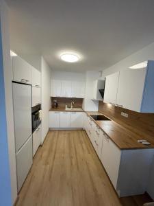 a kitchen with white cabinets and a wooden floor at Apartmán Hron Zvolen in Zvolen