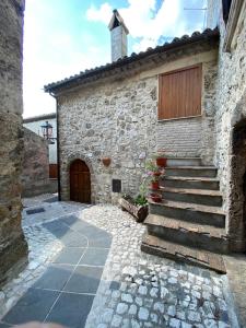 a stone building with a wooden door and stairs at Casa di montagna nei monti simbruini in Trevi nel Lazio
