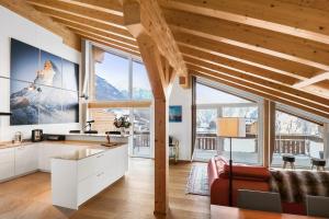 a kitchen and living room with large windows at Matterhorn Penthouse Grächen in Grächen