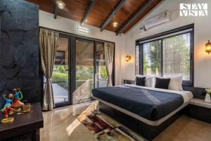 a bedroom with a bed and a large window at StayVista at Blisswood Cottage with Pool & Bar in Nashik