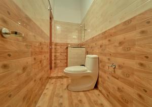 a bathroom with a toilet and wooden walls at Silver Dale Tea Estate Bungalow Ooty by VOYE HOMES in Ooty +47 photos