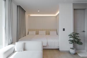 a white bedroom with a bed and a white couch at Marant Residence Hotel Busan Station in Busan