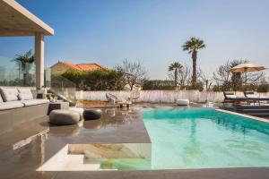 a swimming pool in a backyard with a couch and an umbrella at Avgi Luxury Villa in Svoronata