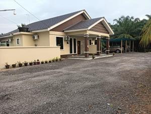 a house with a gravel driveway in front of it at HOMESTAY DESA TERATAI in Kampong Ulu Chuchoh