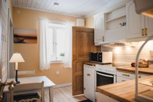 a kitchen with white cabinets and a microwave at Gårdshotell Klockargården Öregrund in Öregrund