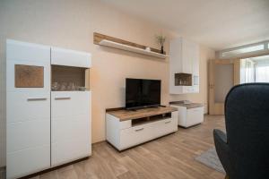 a living room with white cabinets and a flat screen tv at Ferienwohnung-mit-Gartenblick in Rechlin