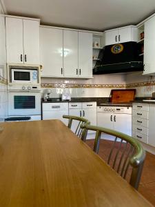 a kitchen with a wooden table and white cabinets at Una casita en el campo dentro de la ciudad in Avila