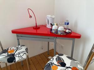 a red table with two chairs and a red table with cups at CHAMBRES D'HÔTES LA MADELEINE in Vienne-le-Château