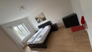 a bedroom with a bed and a window and a red chair at HITrental Stauffacher Apartments in Zürich