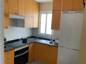 a kitchen with wooden cabinets and a sink and a refrigerator at Appartamento Sinestesia Oceanica in Puerto del Rosario +24 photos