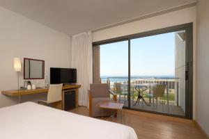 Una habitación de hotel con una cama, un escritorio y un balcón. en Catalonia Barcelona Beach, en Barcelona