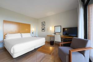 Una habitación de hotel con una cama, una silla y un televisor. en Catalonia Barcelona Beach, en Barcelona