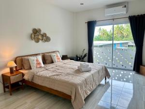 a bedroom with a large bed and a balcony at Twins cafe & Room in Suratthani