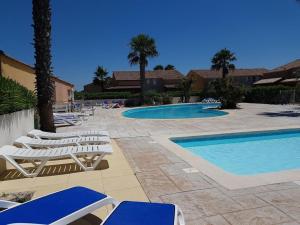 a group of lounge chairs and a swimming pool at Maisonnette résidence Le Grand Bleu in Vendres-Plage