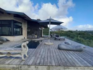 a house with a wooden deck with a pool and an umbrella at Heaven's Door Main House in Stilbaai +14 photos