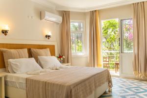 a bedroom with a bed with white sheets and windows at Chillos Beach in Marmaris