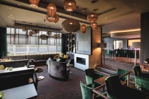 a restaurant with green chairs and a bar at Balmer See – Hotel•Golf•Spa in Balm