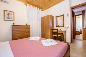 a bedroom with a pink bed with towels on it at Anthi Villa in Alyki