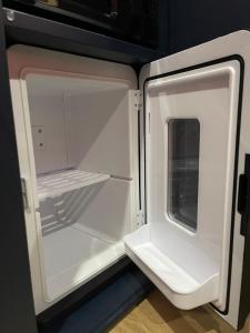 an empty refrigerator with its door open in a kitchen at Le boudoir rouge - Loveroom luxueuse pour couples in La Ferté-Gaucher