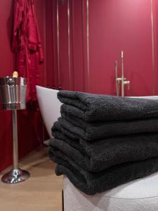 a pile of black towels sitting on top of a bath tub at Le boudoir rouge - Loveroom luxueuse pour couples in La Ferté-Gaucher