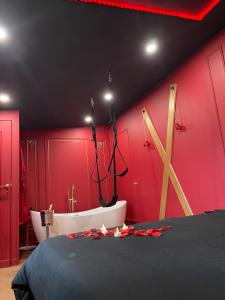 a room with a red wall with a bath tub and a bed at Le boudoir rouge - Loveroom luxueuse pour couples in La Ferté-Gaucher