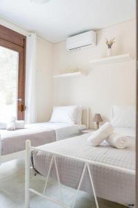 a white bedroom with two beds and a window at Terra Blue Suites - Nefeli in Kalyves