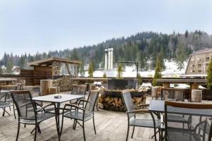 a patio with tables and chairs and a fire pit at Apartman C437 Aparthotel Vucko Jahorina privatni apartman in Jahorina