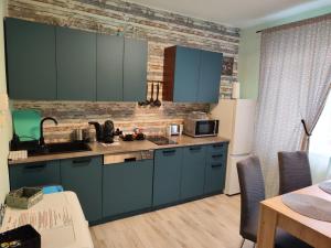 Veludo Apartments Centrum free parking في بانسكا بيستريتسا: مطبخ مع دواليب زرقاء وجدار من الطوب