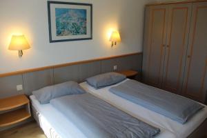 a bedroom with two beds and two lamps on the wall at Ferienhaus Nr 48, Kategorie Komfort, Feriendorf Hochbergle, Allgäu in Lechbruck