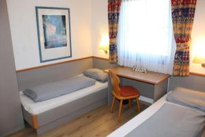 a bedroom with two beds and a desk and a chair at Ferienhaus Nr 48, Kategorie Komfort, Feriendorf Hochbergle, Allgäu in Lechbruck +10 photos