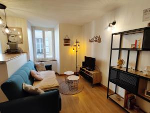 a living room with a blue couch and a tv at Le Nomézia in Ax-les-Thermes