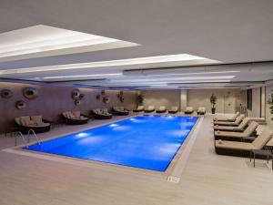 a hotel lobby with a large blue swimming pool at Mövenpick Living Istanbul Saklivadi in Istanbul