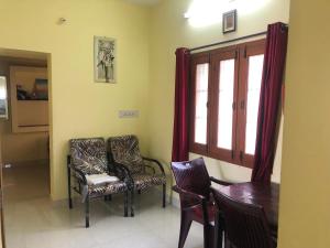 a room with two chairs and a table and a window at Aishwarya Nivas in Palni