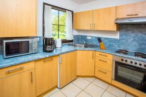 a kitchen with wooden cabinets and a microwave and a sink at Ferienhaus Nr 49, Kategorie Premium, Feriendorf Hochbergle, Allgäu in Lechbruck