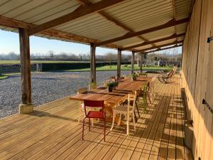 a wooden deck with a table and chairs on it at Le Vert Buisson in Cartigny-lʼÉpinay