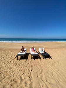 three people sitting in lounge chairs on the beach at Coastal Heaven in Bentota