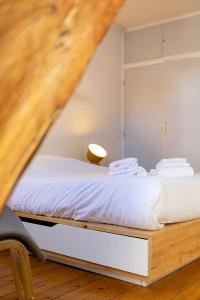 a bedroom with a bed with white sheets and a chair at LA Plume aux pieds du Parvis Saint Jean in Dijon +2 photos